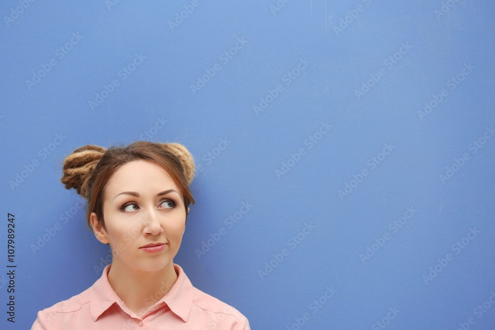 Attractive young blond girl against blue wall.