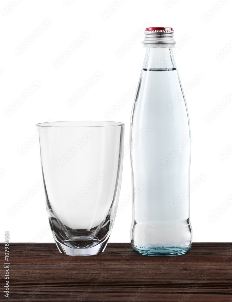 Mineral water in bottle and clean glass on wooden table on grey background Mineral water in bottle and clean glass on wooden table on grey background