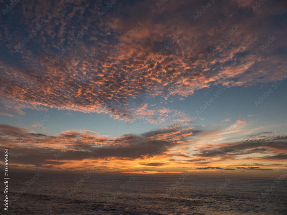 Sunset over the Atlantic Ocean composing a dramatic orange cloud