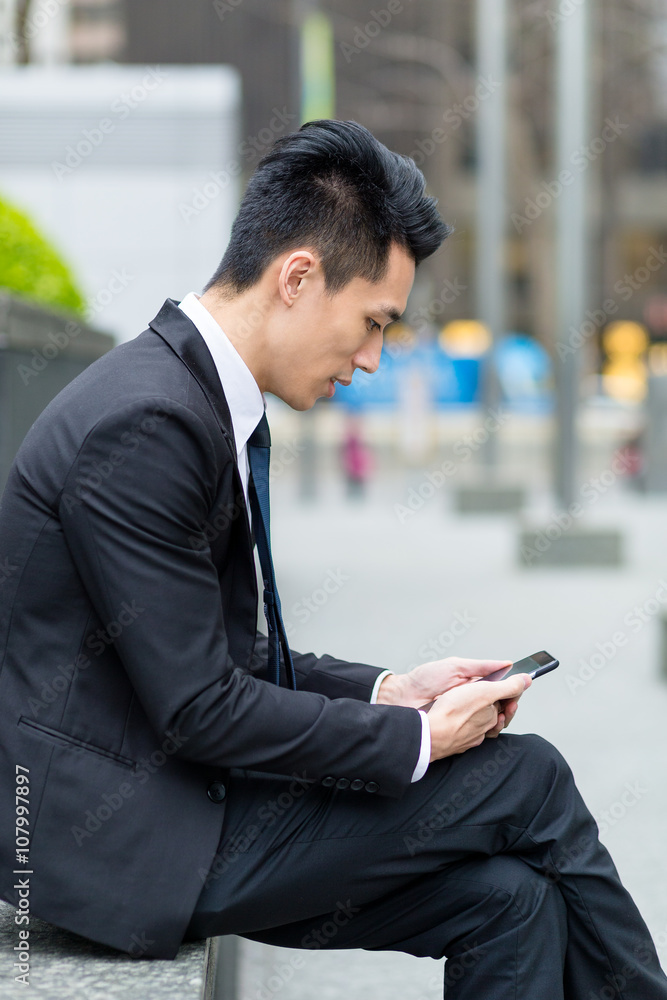 Businessman use of mobile phone and sitting outside Businessman use of mobile phone and sitting outside