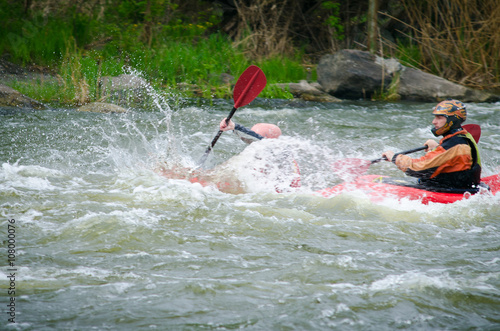 Two kayakers paddling hard the kayak with lots of splashes. active kayakers on the rough water. alloy high speed, motion blur, active family rest in the spring 