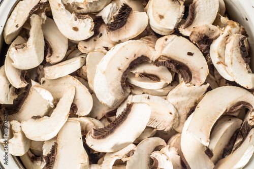 Background with mushrooms champignon sliced and arranged in pot,