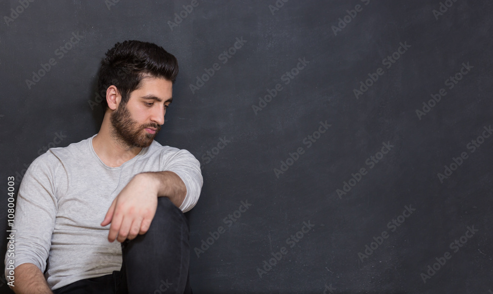 Happy young man looking up to blank  dark chalkboard