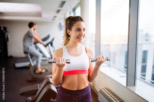 Beautiful woman lifting weights in gym