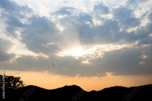 Sunlight in cloudy sky with silhouette mountain