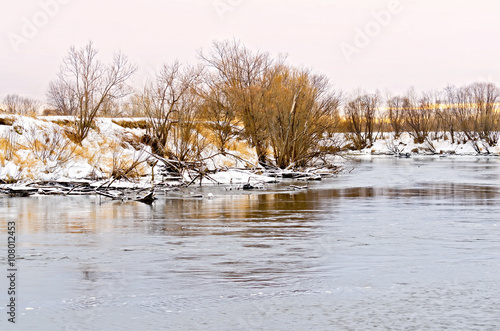 River and the snow-covered beach with trees