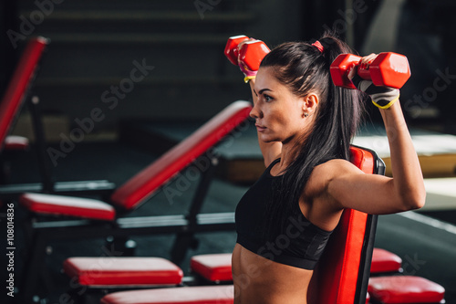 young sporty woman doing exercises with dumbbells in the gym