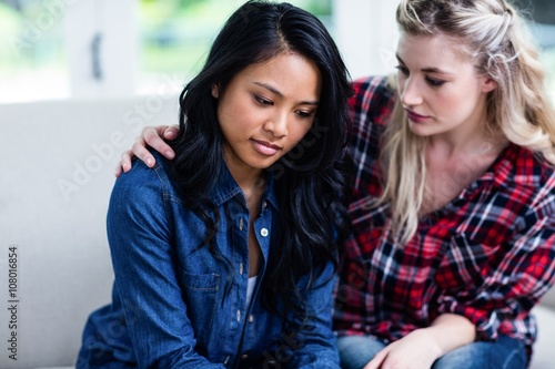 Young woman consoling depressed female friend