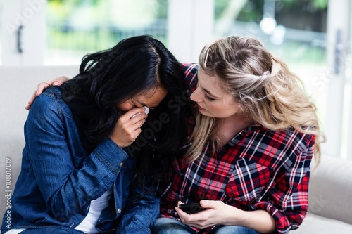 Photo Young woman consoling crying female friend at home