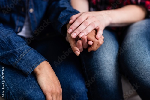 Midsection of female friends holding hands