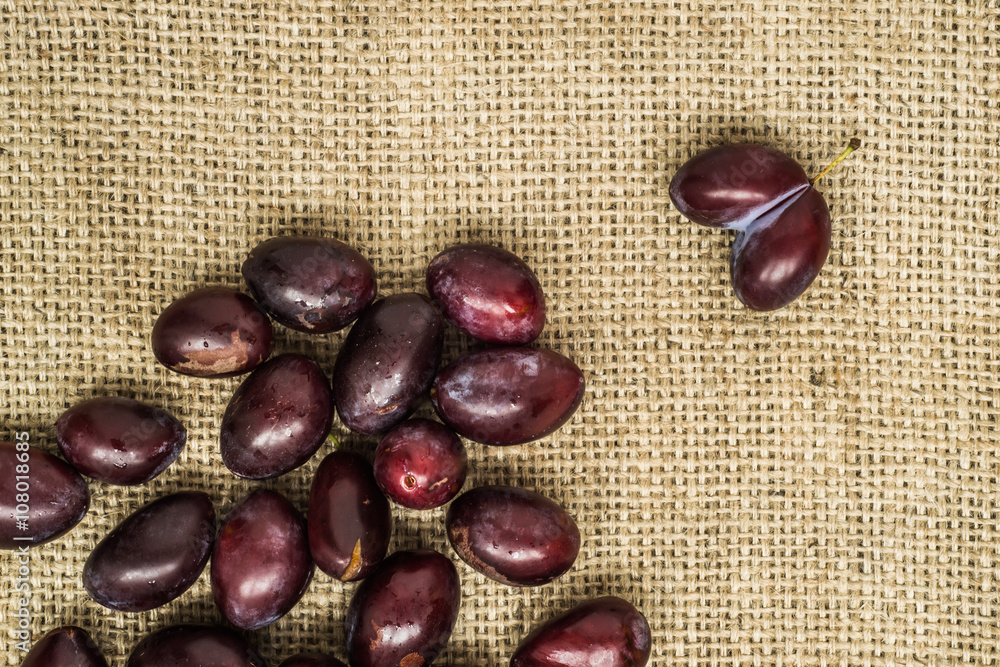 Obraz premium Fresh prune plums in basket on canvas background..