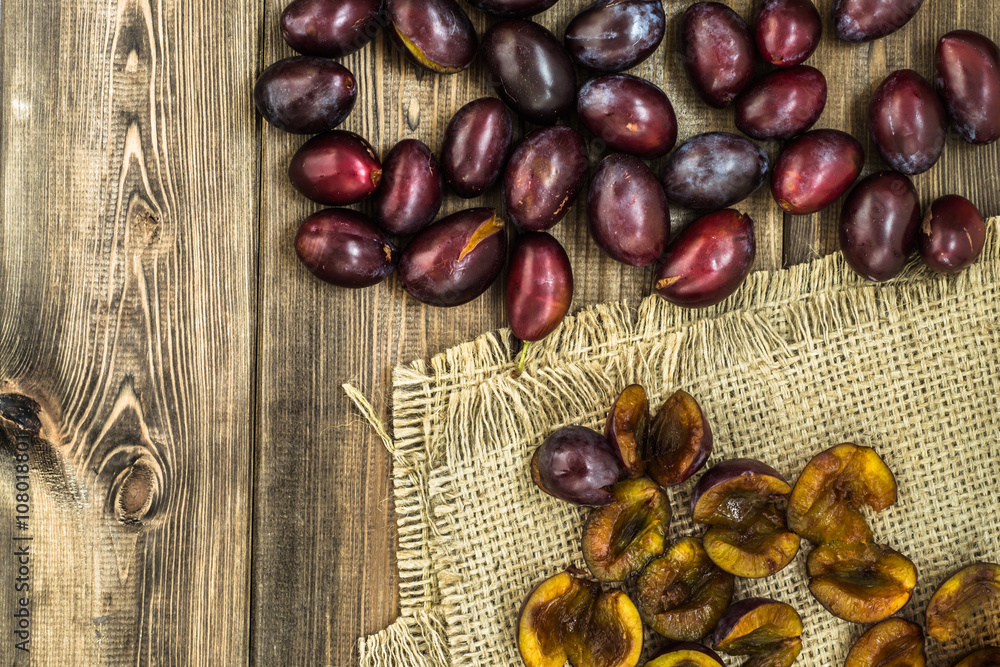 Obraz premium Fresh prune plums on wood background.