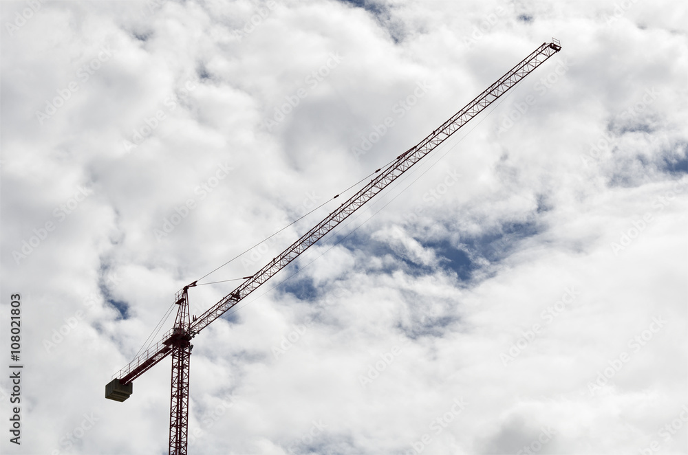 Construction crane in front of a blue sky full of white clouds Construction crane in front of a blue sky full of white clouds