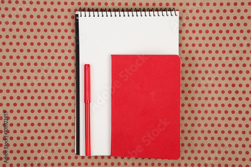 notepads with pen on craft paper background in red polka dots