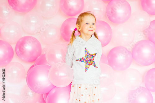 little girl playing with pink balloons