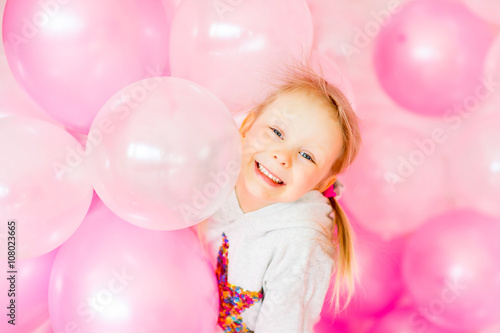 little girl playing with pink balloons