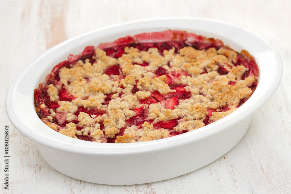 oatmeal strawberry crumble in white dish on white wooden background oatmeal strawberry crumble in white dish on white wooden background