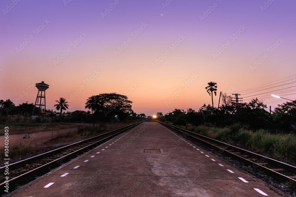 Train moving to the station in sunset