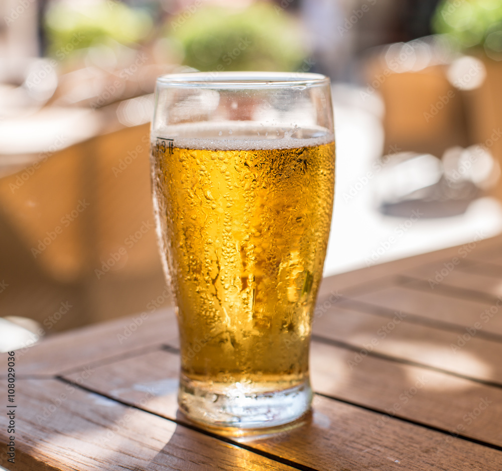 Glass of light beer on the wooden table.