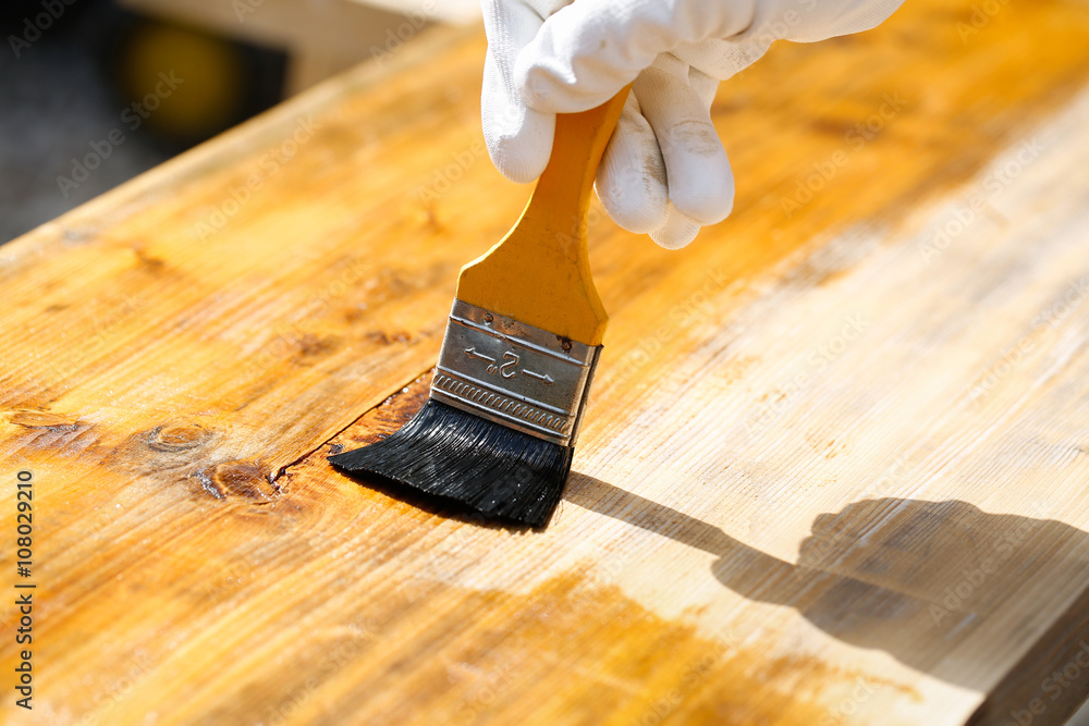 Painter painting wooden surface, protecting wood