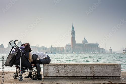 Parent Leaning Toward Stroller by Venetian Waterfront