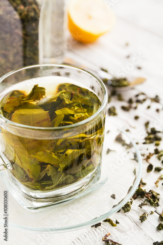 Cup of green tea and lemon and spoon on a wooden table