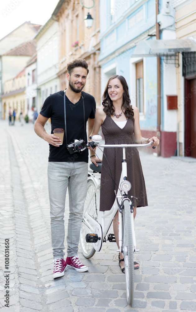 handsome man with a camera and beautiful girl with her bike