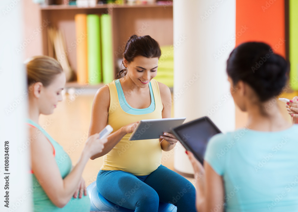 happy pregnant women with gadgets in gym happy pregnant women with gadgets in gym