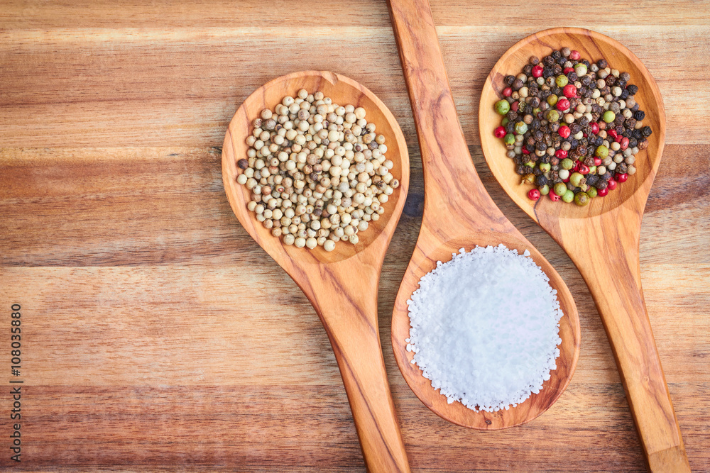 Spices peppercorns and sea salt in spoons on wooden background Spices peppercorns and sea salt in spoons on wooden background