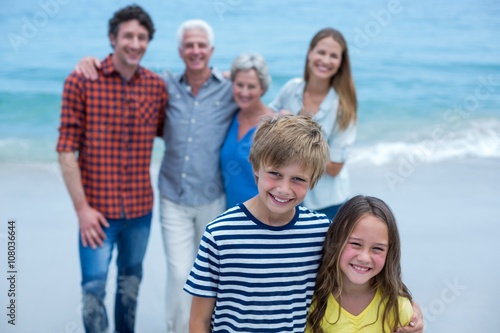 Portrait of siblings with family standing in background