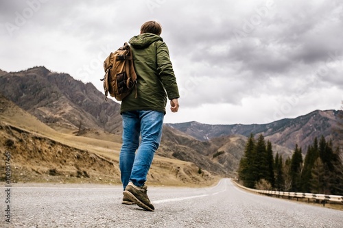 Canvas Print a man with a backpack walks alone on a mountain road
