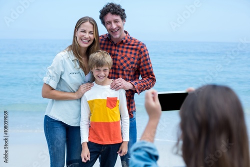 Girl photographing cheerful family at sea shore © WavebreakmediaMicro