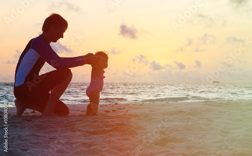 Silhouette of father and little daughter walking at sunset
