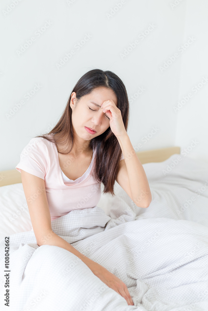 Woman feeling dizzy and sitting on bed Woman feeling dizzy and sitting on bed