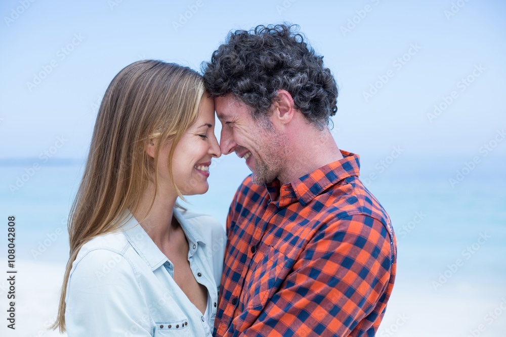 Happy couple standing face to face at sea shore Happy couple standing face to face at sea shore