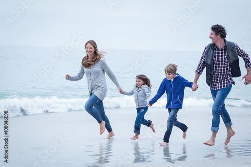 Cheerful family running at sea shore 