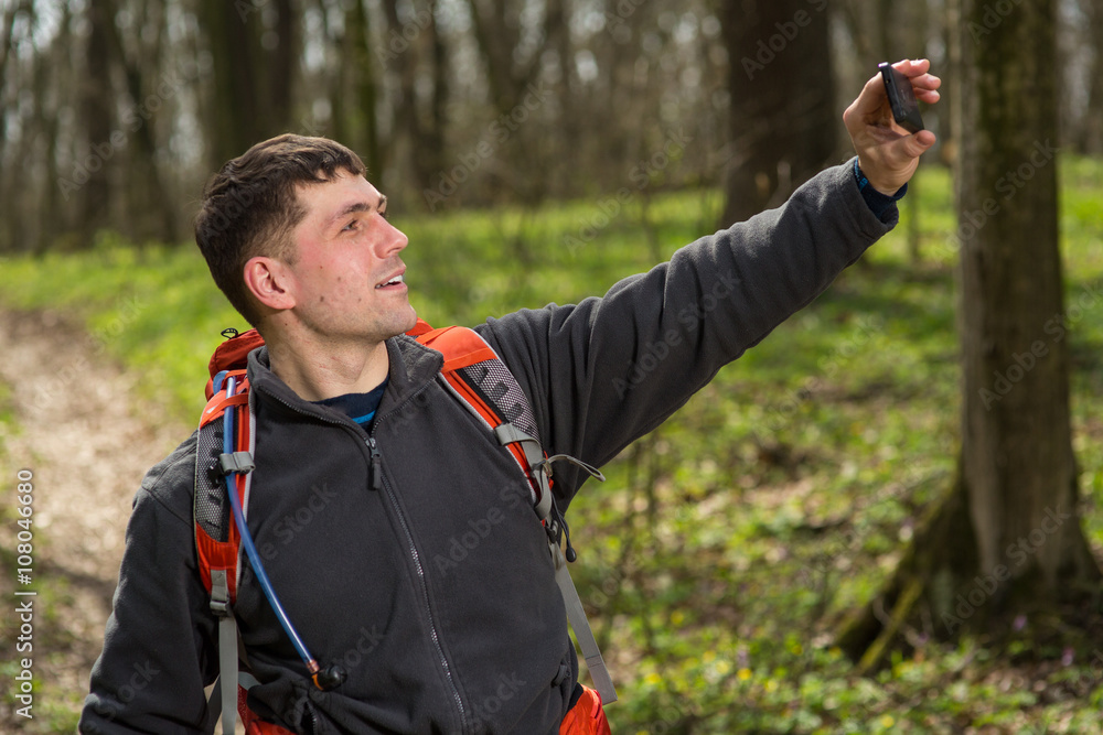 Fototapeta premium Man hiker taking photo with smart phone in forest