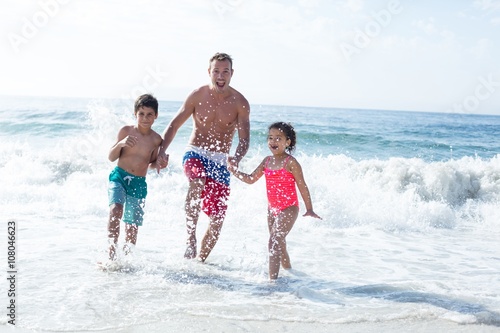 Father enjoying with children in shallow water