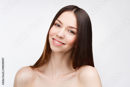 Young beautiful brunette woman with natural makeup on grey backg