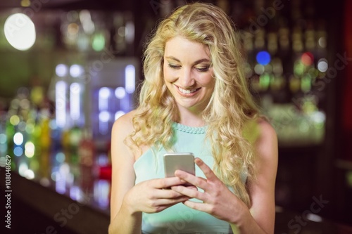 Smiling blonde woman using smartphone