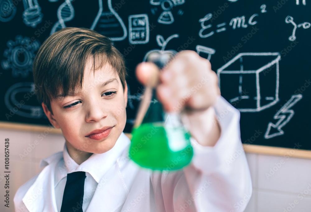 Serious boy looking flask with chemical liquid