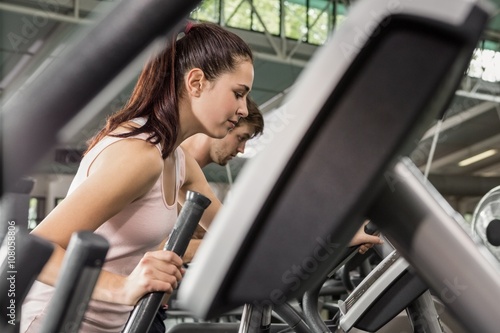 Beautiful woman and man exercising on the elliptical machine