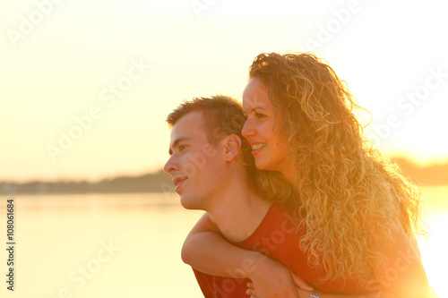 couple piggyback beside a lake at sunset © dobok