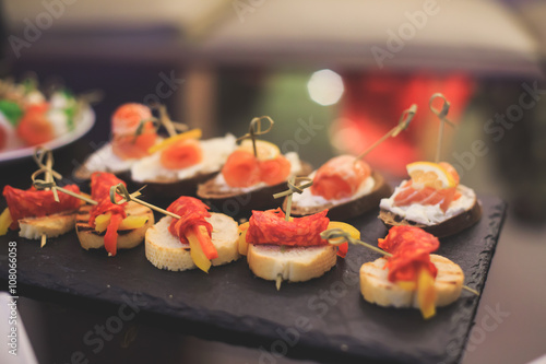 Beautifully decorated catering banquet table with different food snacks and appetizers with sandwich, caviar, fresh fruits on corporate christmas birthday party event or wedding celebration