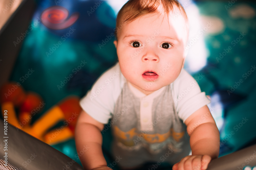 Cute little baby boy playing in colorful playpen, indoors. Beautiful child having fun at nursery. Cute little baby boy playing in colorful playpen, indoors. Beautiful child having fun at nursery.