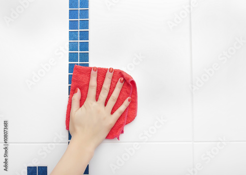 Female hand a rag washes the tile. photo