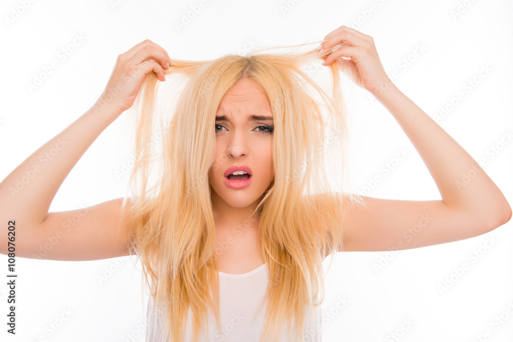 Portrait of upset woman looking at her damaged hair Portrait of upset woman looking at her damaged hair