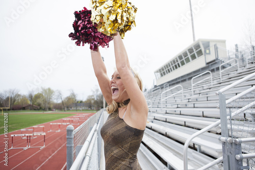 Caucasian cheerleader cheering on bleachers photo