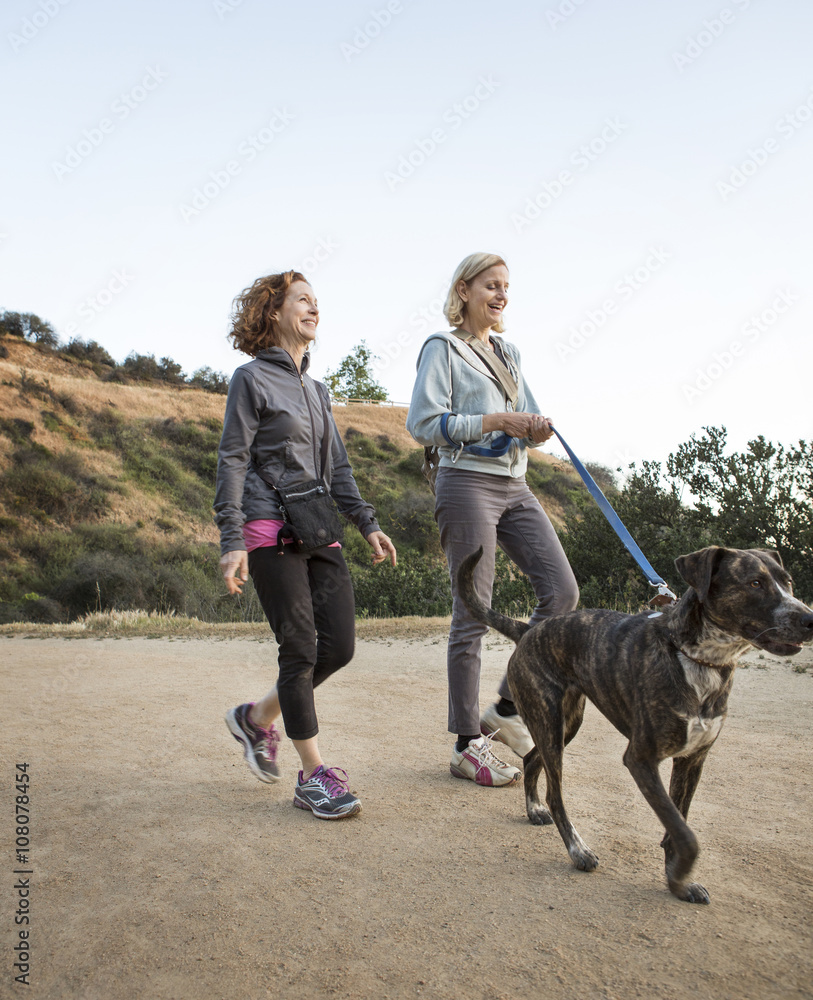Caucasian women walking dog on dirt path Caucasian women walking dog on dirt path