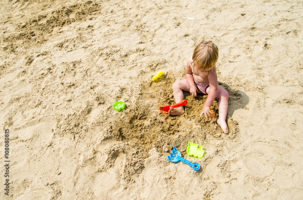 Caucasian girl playing in sand on beach Caucasian girl playing in sand on beach